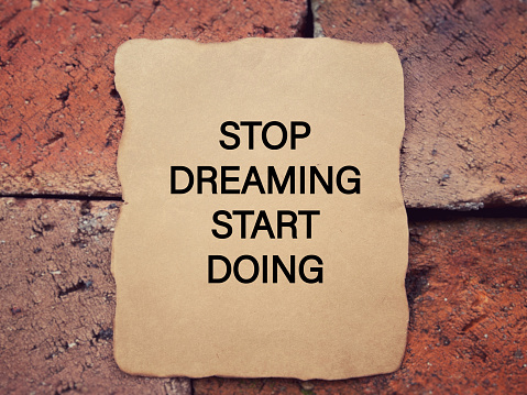 STOP DREAMING START DOING written on a paper. With blurred style background.