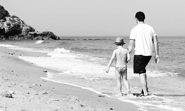 istock father and son walking together on the beach 178618906