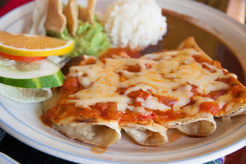 Some enchiladas with cheese and tomato