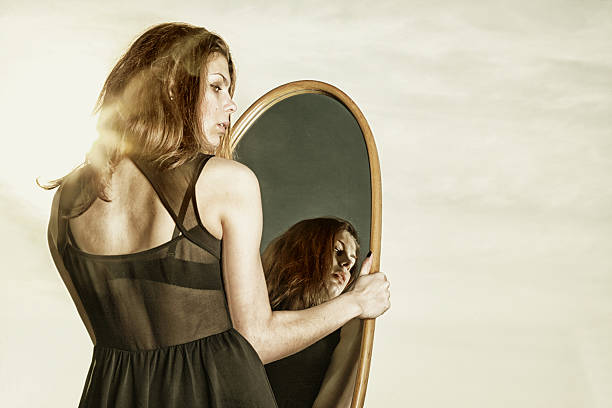 istock thoughtful woman looks at the reflection in mirror 178619959
