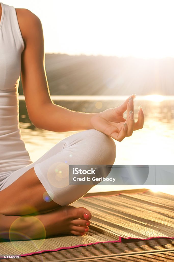 Young woman meditating on the beach Beautiful young woman yoga on the lake in a white dress Outdoors Stock Photo