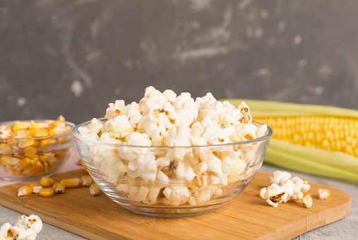 Prepared popcorn with ingredients on wooden table