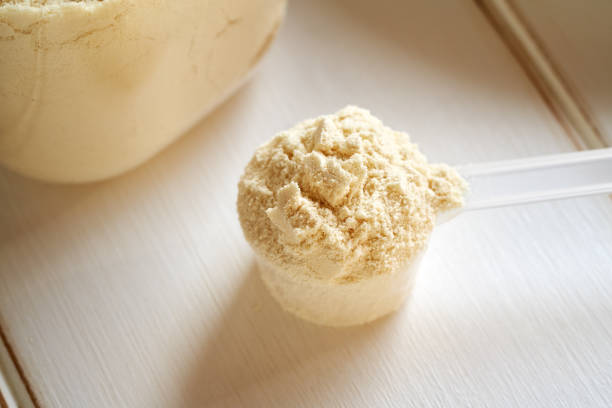 proteine del siero di latte in polvere aromatizzate alla vaniglia in un misurino di plastica - whey protein concentrate foto e immagini stock