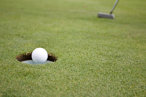 Golf ball falling into golf cup, frozen motion.