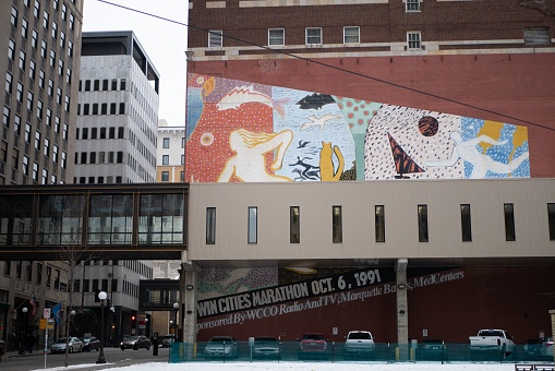 Saint Paul, United States – February 05, 2019: A street scene of an urban cityscape, featuring a mural on a building and parked cars