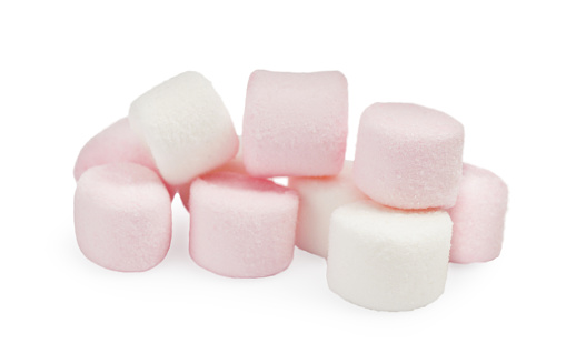 White sugar cubes and a teaspoon on pastel pink background