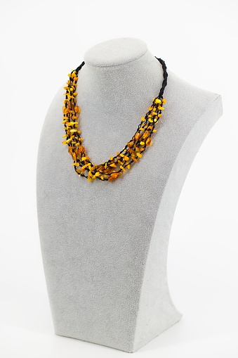 A polished amber necklace elegantly threaded on a black cord. The golden-brown hues of the Baltic amber create a warm, natural aesthetic. The minimalist design and sleek black cord highlight the gem's beauty. A fusion of organic simplicity and timeless elegance, this necklace is a stylish accessory with cultural and artisanal appeal.