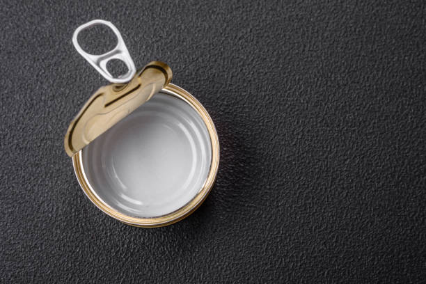 Empty round uncorked metal can for canned meat or fish on a dark concrete background