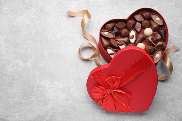 istock Heart shaped box with delicious chocolate candies and ribbon on light grey table, flat lay. Space for text 1786291918