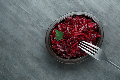 Tasty red cabbage sauerkraut with parsley on grey table, top view. Space for text