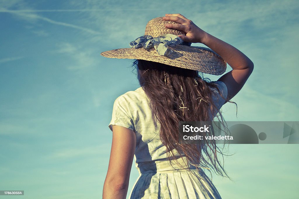Beautiful 20's retro girl holding straw hat on her head Beautiful 20's retro girl holding her straw hat on head with hand. 20-29 Years Stock Photo