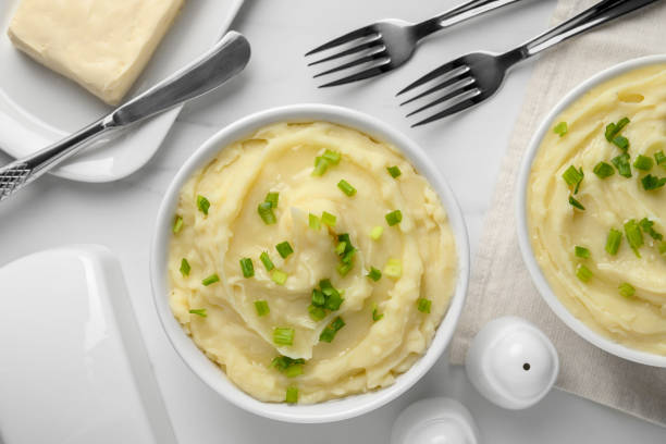 istock Bowls of delicious mashed potato with green onion on white table, flat lay 1786308088