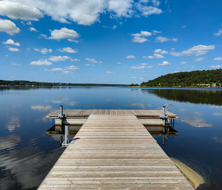 Wooden piers overlooking the lake in the sun and clouds in the blue sky. Spring
