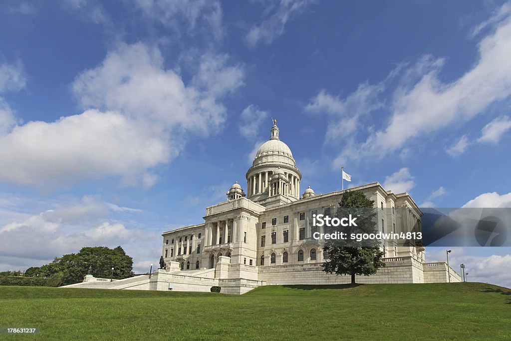The Rhode Island State House on Capitol Hill in Providence Wide-angle view of the front of the Rhode Island state capitol building as it sits on Capitol Hill in Providence with bright blue sky and white clouds in the background. The building is covered with white Georgia marble and was constructed from 1895 to 1904. State Capitol Building Stock Photo