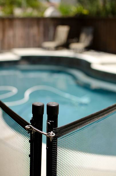 pool fence two poles holding up a netted pool fence with a shallow depth of field. pool gate stock pictures, royalty-free photos & images