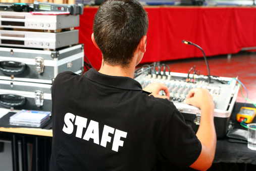 A sound technician, wearing a t-shirt staff noted in the back. Focus on white STAFF letters on black background of tee-shirt.