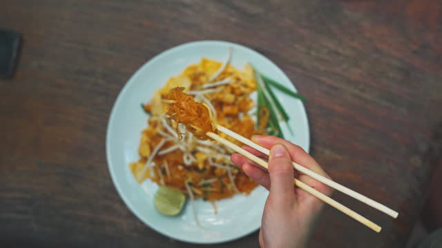 Directly above shot of woman eating pad Thai with chopsticks