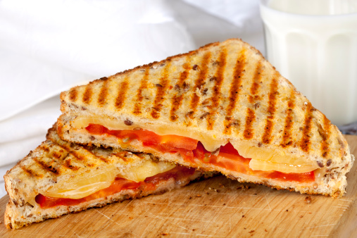 Grilled tomato and cheese sandwich with a glass of milk.