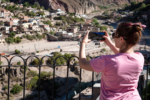 Tourist taking a photo of the beautiful town of Iruya, Salta, Argentina. Tourist touring northern Argentina. Young woman on vacation taking a photo of the landscape