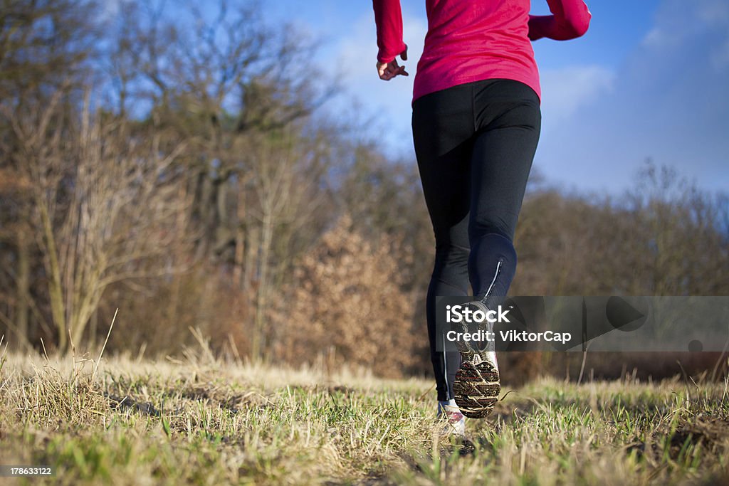 Jogging outdoors in a meadow "Young woman jogging outdoors in a meadow (shallow dof, focus on the running shoe)" Active Lifestyle Stock Photo