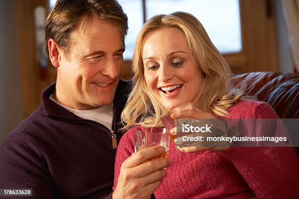 Medio De Pareja Sentada En El Sofá Con Gafas De Whisky Foto de stock y más banco de imágenes de Vida doméstica