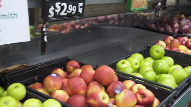 Tracking Shot of Bins of Apples on Supermarket Shelves