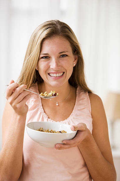 istock Beautiful young woman holding bowl with cereal smiling 178636106
