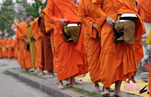 11/07/2019 Shwedagonm pagoda, Yangon, Myanmar\nSenior monk in orange traditional buddhist dress walking inside the temple on white marble floor