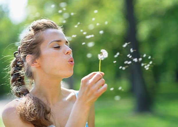 istock Young woman blowing away dandelion 178636323