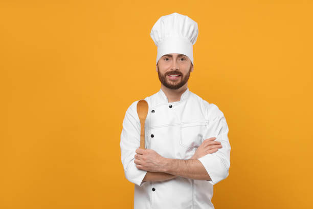istock Smiling mature chef with spoon on orange background, space for text 1786365648