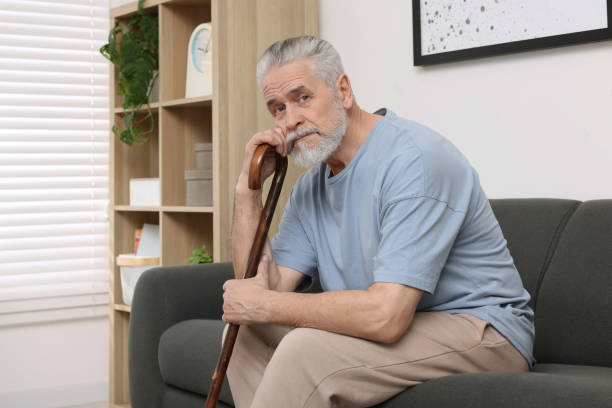 istock Senior man with walking cane sitting on sofa at home 1786383692