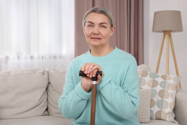 istock Senior woman with walking cane sitting on sofa at home 1786385867