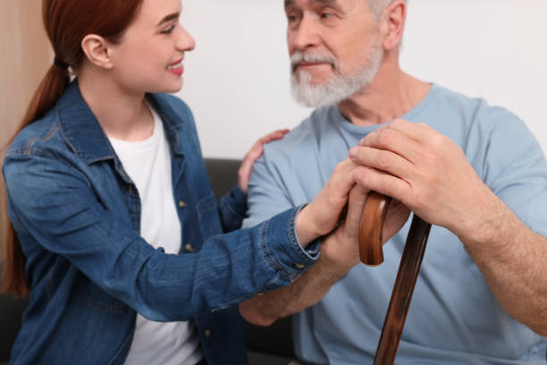 istock Caregiver and senior man with walking cane on sofa at home, selective focus 1786386079
