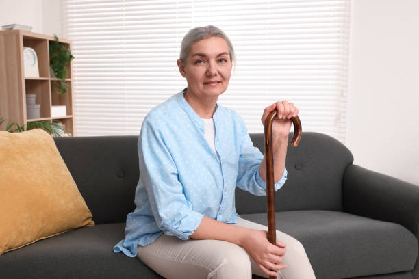 istock Senior woman with walking cane sitting on sofa at home. Space for text 1786386215