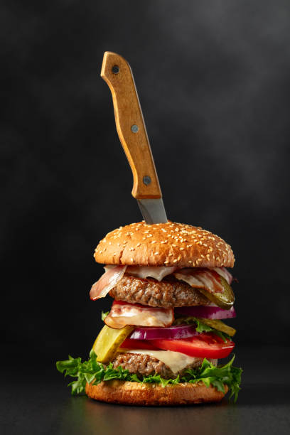 istock Fresh tasty burger with knife on a black background. 1786390776