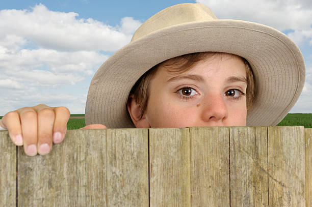 istock boy with cowboy head looking above a wooden gate 178639530