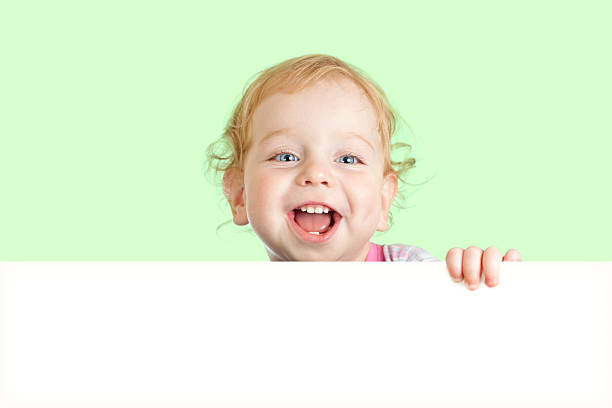 istock Happy child face behind blank advertising banner. Banner and gre 178640193