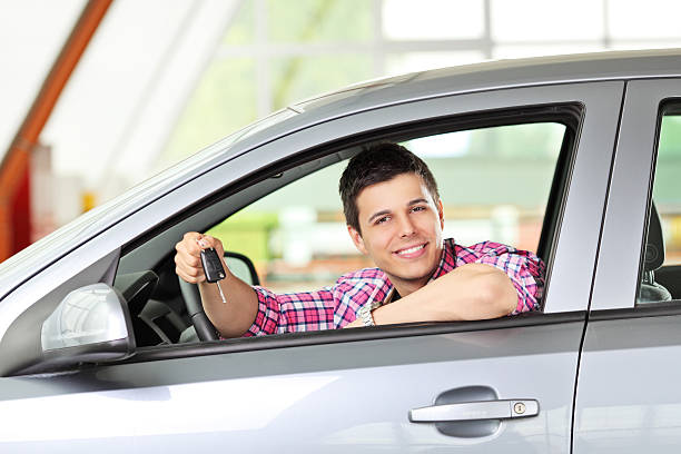 istock Smiling male sitting in his automobile and holding a key 178640419