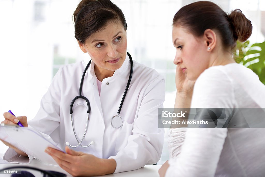 Female doctor and female patient looking over clipboard doctor explaining diagnosis to her female patient Doctor Stock Photo