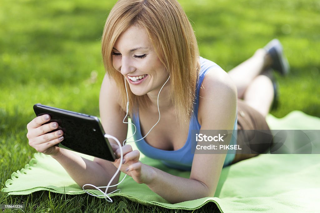 Woman lying on grass with digital tablet Adult Stock Photo