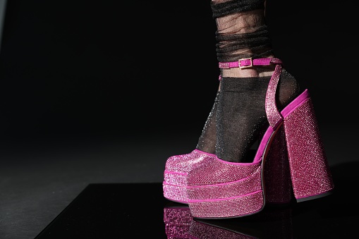 Woman wearing pink high heeled shoes with platform and square toes on black background, closeup. Space for text