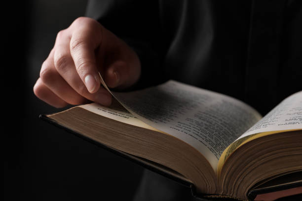 istock Woman reading holy Bible on black background, closeup 1786415045