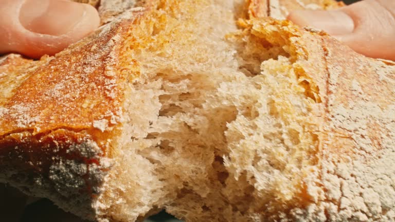 Baker breaking hot and fresh bread. Male baker hands breaking homemade bread.