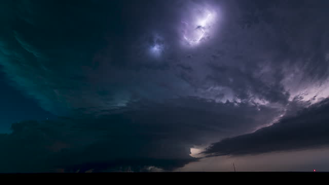 A massive supercell churns through the New Mexico landscape after dark. Stars shine as the storm spins into the night.
