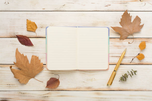 istock Autumn leaves with notebook on wooden background, top view 1786427073
