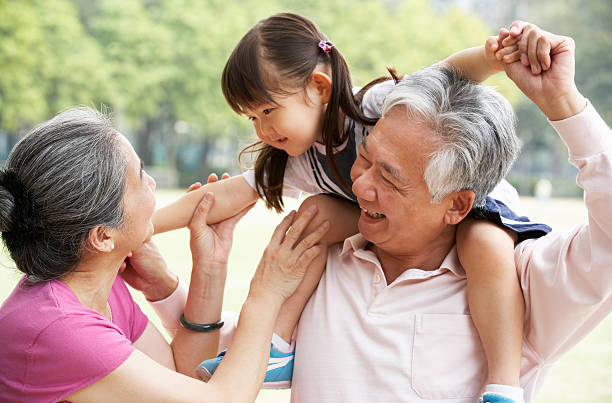 Chinese Grandparents Giving Granddaughter Ride On Shoulders Chinese Grandparents Giving Granddaughter Ride On Shoulders Smiling china chinese ethnicity smiling grandparent stock pictures, royalty-free photos & images