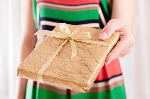 Young woman holding Christmas present box wrapped in golden paper