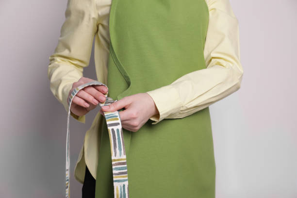 istock Woman putting on green apron against white wall, closeup 1786436062
