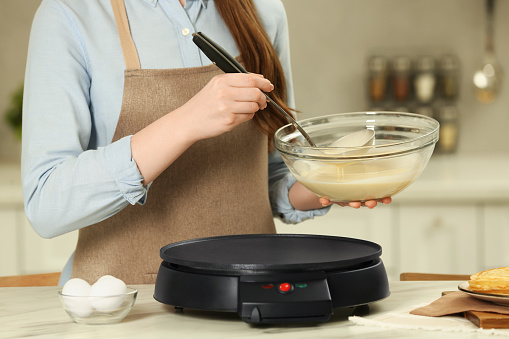 Woman with dough for crepes at white marble table in kitchen