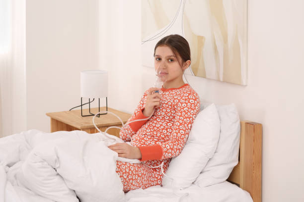 istock Cute girl using nebulizer for inhalation on bed at home 1786437643